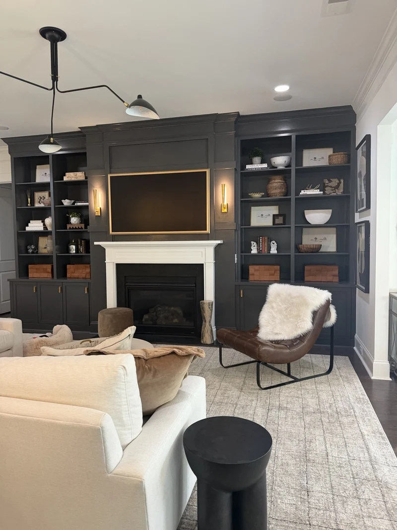 A charcoal living room with layered textiles, books and collected objects.